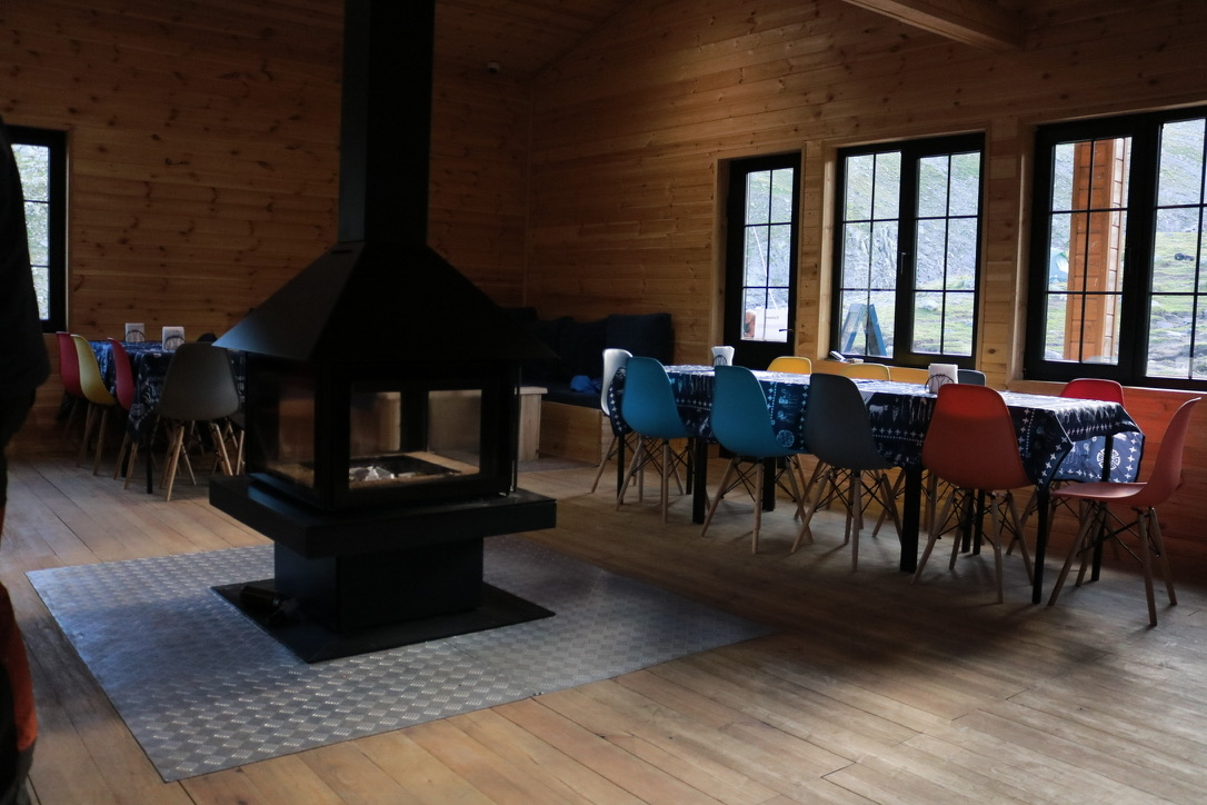 The dining area and wood stove of Georgian mountain hut Deka - looking out the window towards mount kazbeg